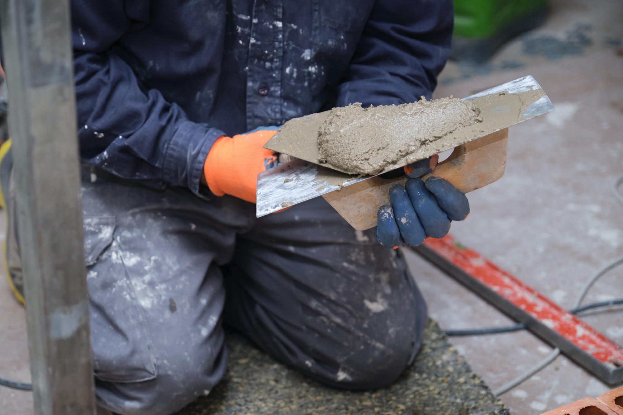 Unrecognizable builder manipulating cement with spreader and trowel.