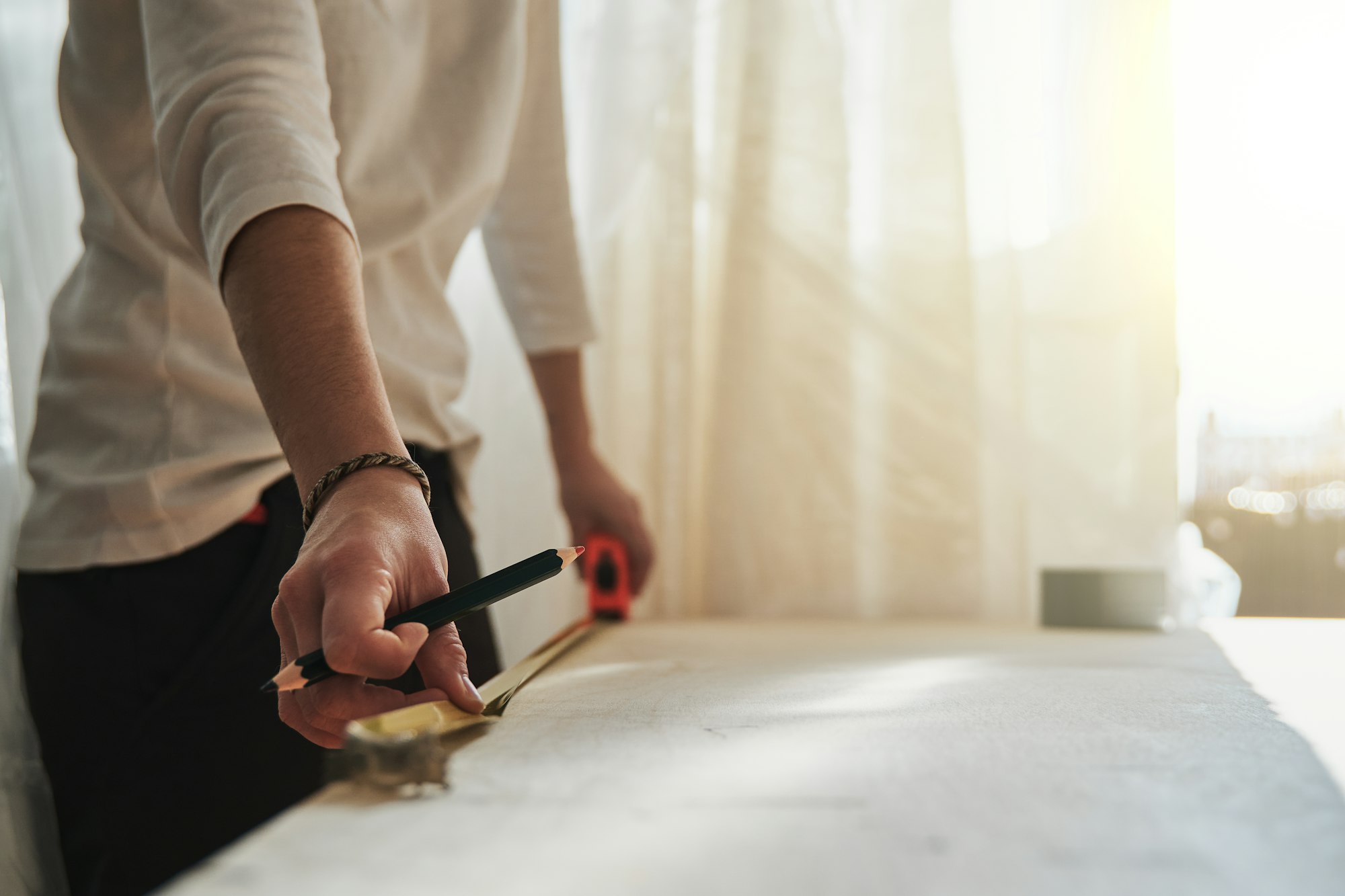 Woodwork and furniture carpenter measuring wood plank while working inside carpentry workshop